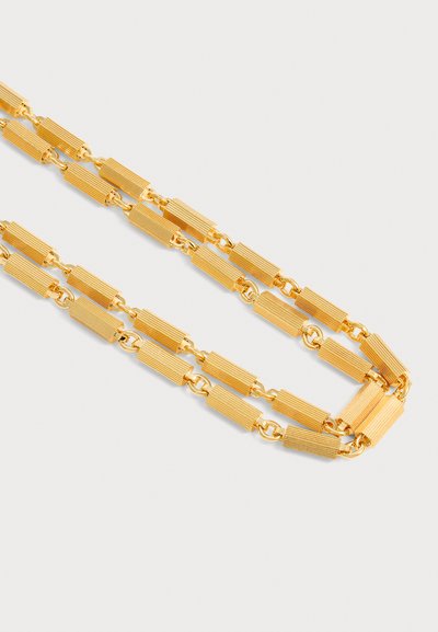 Collier chaîne en or avec des maillons rectangulaires texturés reliés par de petits maillons ronds sur un fond clair uni.