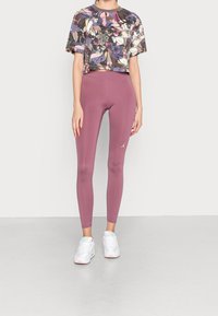 Kortärmad, cropped t-shirt med ett blommönster i flera färger som matchas med högmidjade, figurnära, mörkrosa leggings.