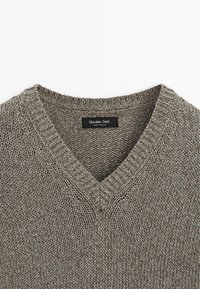 Szary sweter dzianinowy z dekoltem w kształcie litery V, posiadający teksturowany wzór oraz metkę z napisem "Massimo Dutti" wewnątrz dekoltu.