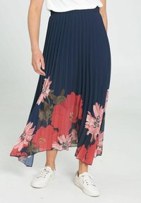 Marininspirerad plisserad kjol med blommönster i rosa och röda nyanser vid fållen, tillverkad av lättviktsmaterial, matchad med vita sneakers.