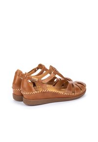 Sandalias de cuero marrón con diseño abierto, presentando correas entrecruzadas y costuras decorativas. Suela texturizada para un mejor agarre y comodidad.