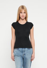 Μαύρο t-shirt με καπελομάνικα από απαλό βαμβάκι, με στρογγυλεμένο ντεκολτέ και εφαρμοστή γραμμή, σε συνδυασμό με ανοιχτόχρωμο μπλε τζιν.