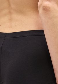 Κοντινή λήψη της κάτω μέσης και της μέσης ενός ατόμου που φοράει μαύρα στενά σορτς ή εσώρουχα.