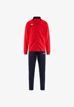 Giacca rossa con zip e dettagli neri, abbinata a pantaloni tuta blu navy. Il materiale sembra liscio, adatto per abbigliamento sportivo.