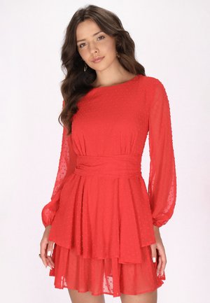 Rotes Kleid mit langen, durchsichtigen Ärmeln, strukturierten Punkten, einem taillierten Oberteil und einem schichtweise gestalteten Rock. Der Stoff wirkt leicht und fließend.