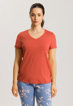 Kortærmet v-hals t-shirt i koralfarve, lavet af bomuld. Glat tekstur med en tætsiddende silhuet. Parret med blå leggings med blomsterprint.