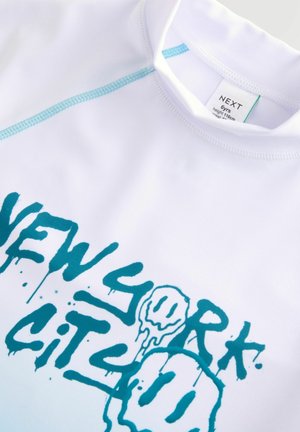 White rash guard featuring blue dripping text print reading "NEW YORK CITY." Includes contrasting stitching along the collar.
