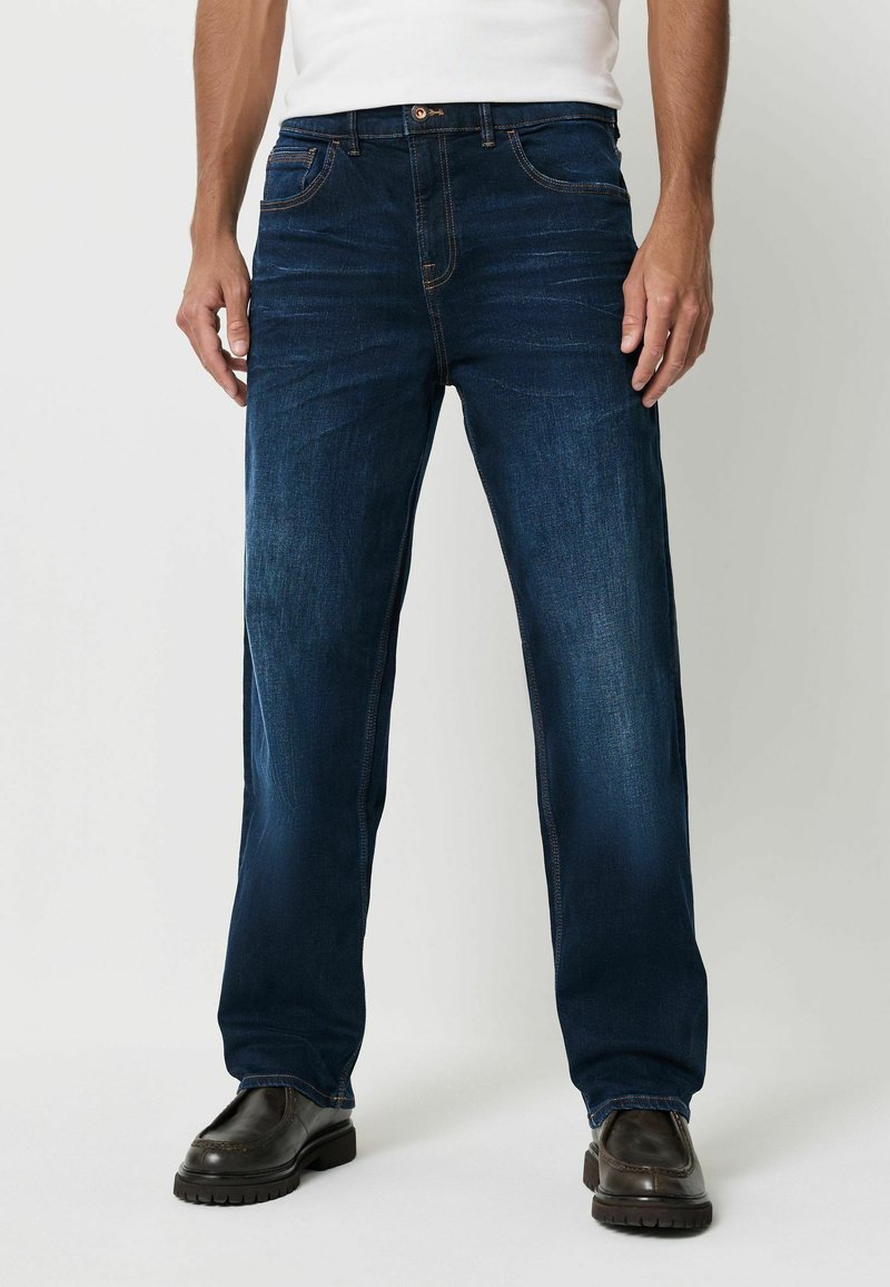 Tmavě modré džíny s rovnými nohavicemi, zdobené oranžovým prošíváním, pěti kapsami a knoflíkovým zapínáním. Texturovaná látka dotváří vzhled.