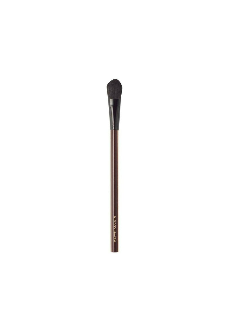 Makeup brush with a tapered, rounded head; soft bristles in black; a slim, metallic bronze handle; engraved lettering near the base.