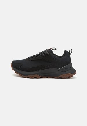 Schwarzer Sportschuh mit einem Obermaterial aus Mesh und Wildleder, Gummisohle, strukturierten Einsätzen und kontrastierenden braunen Traktionsnoppen. Verfügt über reflektierende Akzente.