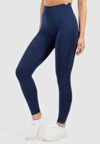 Marinblå leggings med hög midja och slät textur, med en åtsittande design och tonalt sömnad längs sidorna.