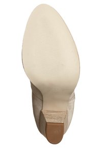Beżowy but na wysokim obcasie z zaokrąglonym noskiem, miękką fakturą zamszu, gładką gumową podeszwą oraz prążkowanym akcentem u podstawy obcasa.