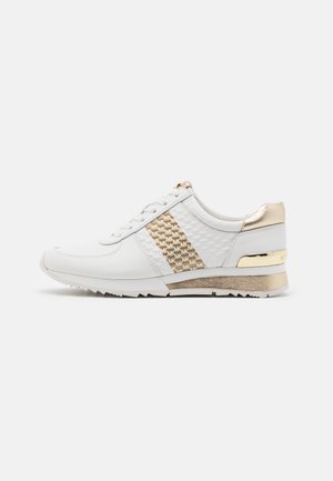 Hvid lædersneaker med gyldne accenter, mønstret sidepanel, hvide snørebånd og rilledsål, vist fra højre side på en ensfarvet baggrund.