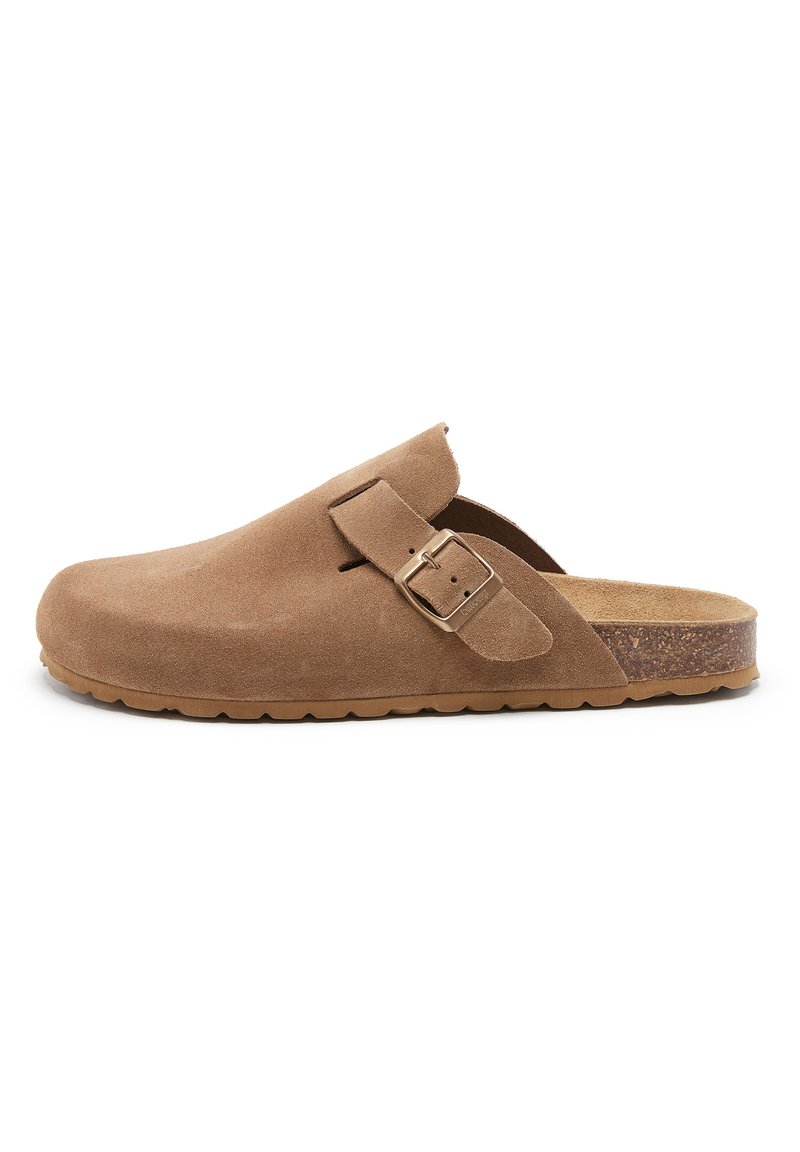 Sabots en daim marron avec une large sangle, une boucle en métal et une semelle intérieure en liège texturée ; semelle en caoutchouc à profil bas pour la stabilité et le confort.