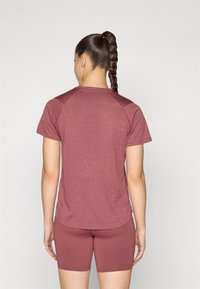 T-shirt de sport couleur framboise à manches courtes et col rond, avec un tissu texturé et des panneaux d'épaule contrastants.