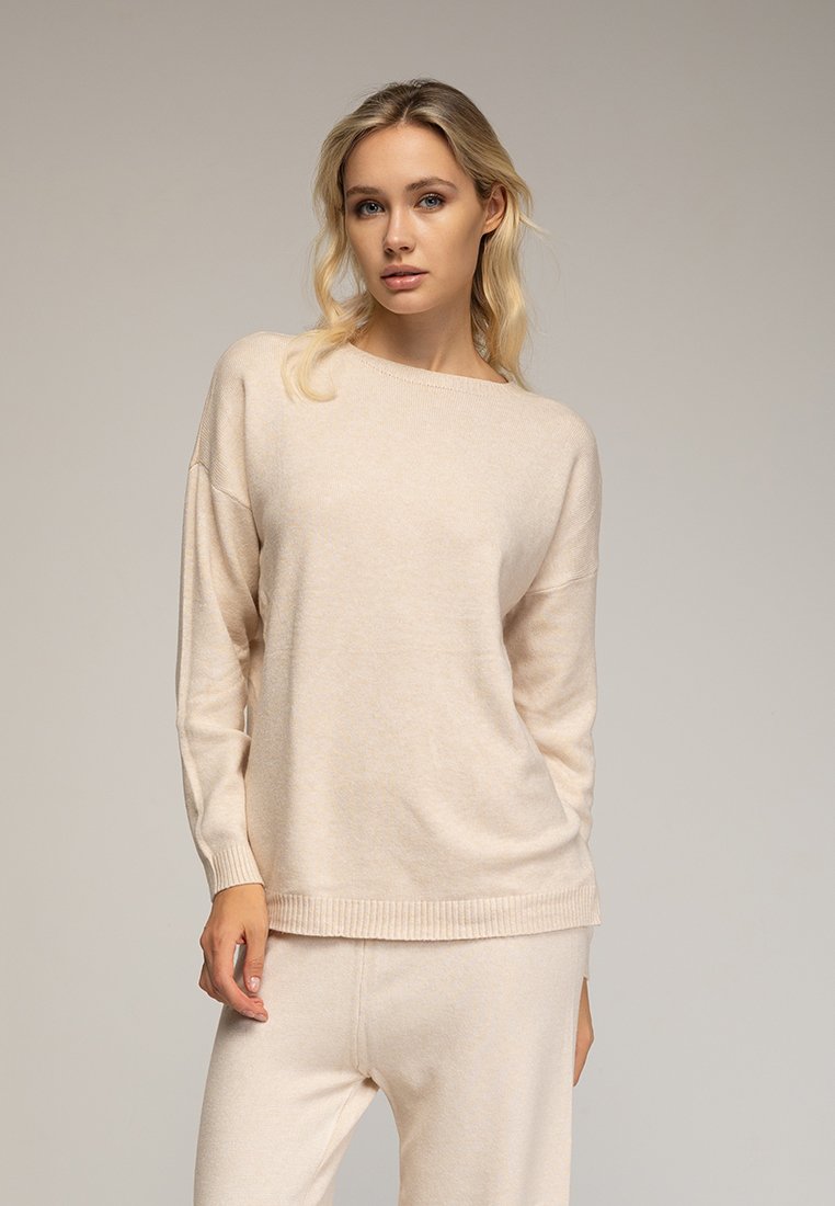 Crème-kleurige trui gemaakt van zachte stof, met een ronde hals, ribgebreide zoom en een ontspannen pasvorm. Glad textuur en wijde mouwen.