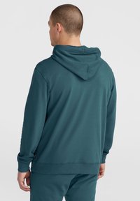Sudadera con capucha en color verde azulado, de manga larga, con un corte relajado y puños acanalados. Textura suave y detalles de costura sutil en la capucha.
