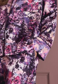 Tuvo plāksne ar satīna pidžamu, kas ir ar purpura, rozā un melna meža izdruku, kurā attēloti koki, truši un staltbriedis.