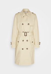 Trench-coat beige à double boutonnage avec ceinture, pattes d'épaule boutonnées, poche avant à rabat et lanières de poignets avec boucles.