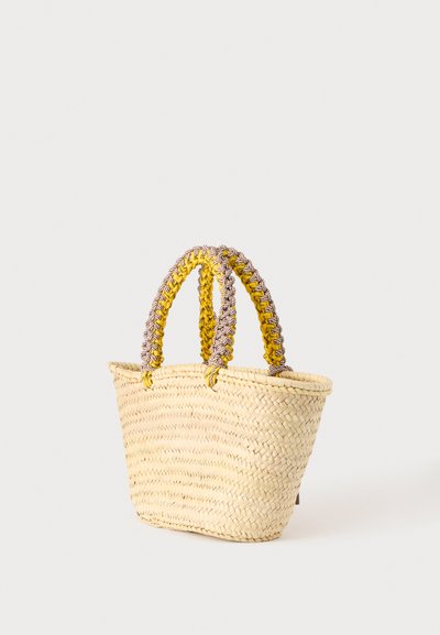 Sac cabas en paille tissée avec de larges anses tressées jaunes et marron sur un fond clair uni.