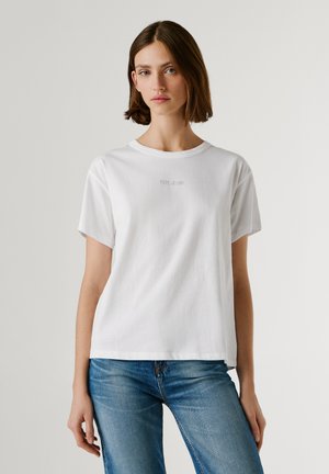 Weißes Baumwoll-T-Shirt mit rundem Ausschnitt und kurzen Ärmeln; verfügt über eine dezente "Pepe Jeans" Stickerei auf der Brust. Kombiniert mit blauen Jeans.