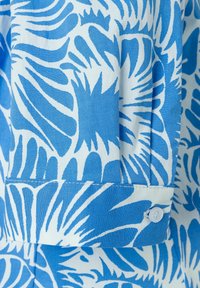 Korte mouwen shirt met een blauw-wit bloemmotief, gemaakt van lichtgewicht stof. Bevat een knoop en een opgerolde manchetdetail.