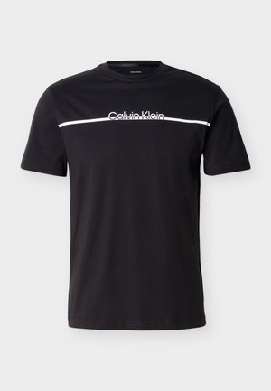 Svart T-skjorte med korte ermer og en hvit horisontal stripe over brystet med "Calvin Klein"-logoen plassert sentrert over stripen.