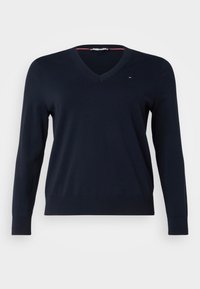 Maglione a V blu navy realizzato in tessuto morbido con maniche lunghe e orlo a costine. Piccolo dettaglio con logo sulla parte superiore del petto a sinistra.