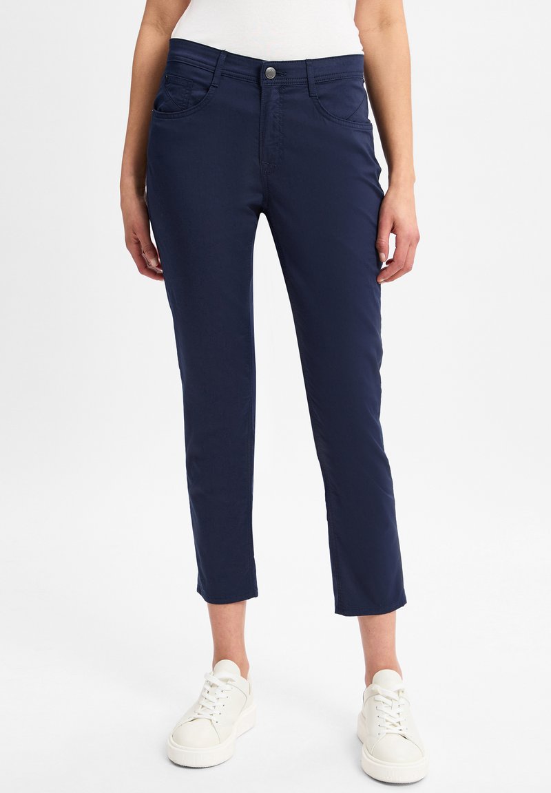 Marineblauwe cropped broek van rekbare katoen, met voorzakken, een knoopsluiting en een gladde textuur. Gecombineerd met witte sneakers.