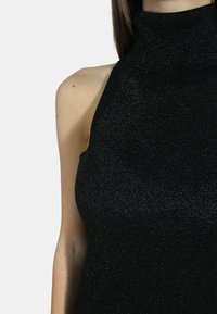 Top senza maniche nero con collo alto, realizzato in tessuto a coste e texture che presenta sottili dettagli luccicanti. Design aderente.