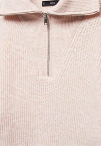 Pull en tricot côtelé rose clair avec une demi-fermeture éclair argentée et un col replié, montrant un tissu à texture douce.