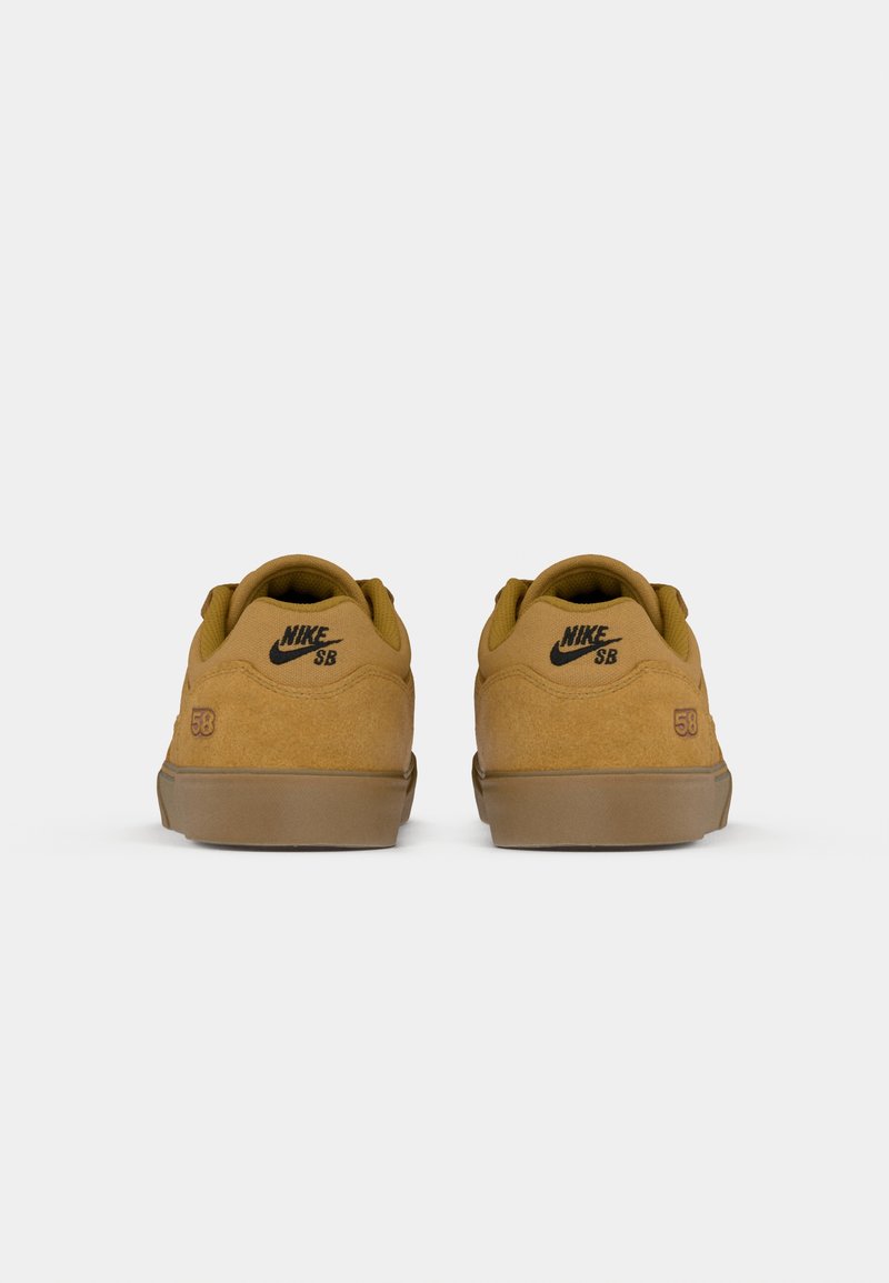 Des chaussures Nike SB en daim beige, avec des semelles en caoutchouc marron. Elles présentent un logo classique et le numéro 58 au talon. Forme arrondie et collier rembourré.