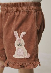 Brune corduroy shorts med volanger og en broderet beige og pink kaninpatch på siden.