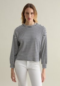 Maglietta a maniche lunghe a righe in blu navy e bianco, scollatura rotonda, vestibilità rilassata, tessuto morbido, con maniche leggermente arricciate e orlo corto.