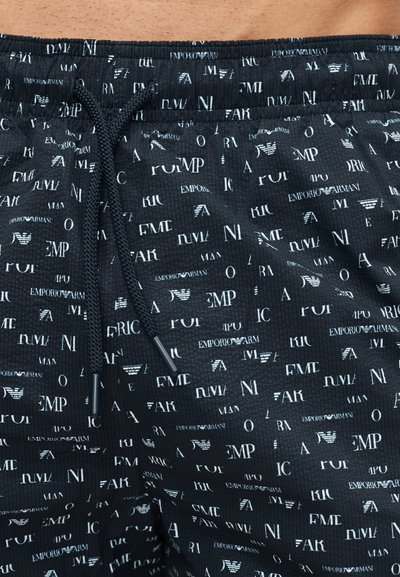 Μαύροι υφασμάτινοι σορτς με λευκά διασκορπισμένα λογότυπα και κείμενο Emporio Armani, με μαύρο κορδόνι στη ελαστική μέση.