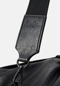 Black leather strap with embossed "lala Berlin" logo, attached to a bag via a metal clip. Textured surface with smooth accents.