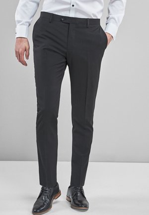 Dark gray slim-fit trousers with a flat front, belt loops, and side pockets, paired with black leather shoes, featuring a smooth fabric texture.