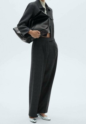 Musta ruudullinen takki yhdistetty vaaleanharmaisiin korkeavyötäröisiin housuihin, hopeanvärisiin teräväkärkisiin kenkiin ja mustaan nahkaiseen olkalaukkuun.