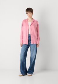 Light pink, textured shirt with a collar and buttons, paired with wide-leg blue jeans and beige shoes. Simple design, relaxed fit.