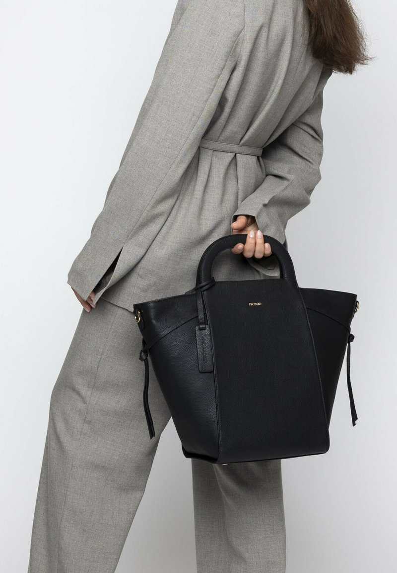 Black leather tote bag with a structured design, rounded top handles, and gold hardware accents. The bag features soft texture and a side tag.
