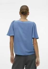 Top corto azzurro a maniche corte con tessuto testurizzato, scollo rotondo e maniche leggermente puffate. Presenta una silhouette semplice e una vestibilità rilassata.
