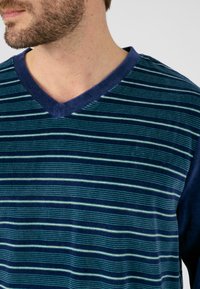 Blauw gestreepte V-hals shirt met donkerblauwe mouwen. Bevat horizontale strepen in verschillende tinten blauw en groen op een zachte textuur.