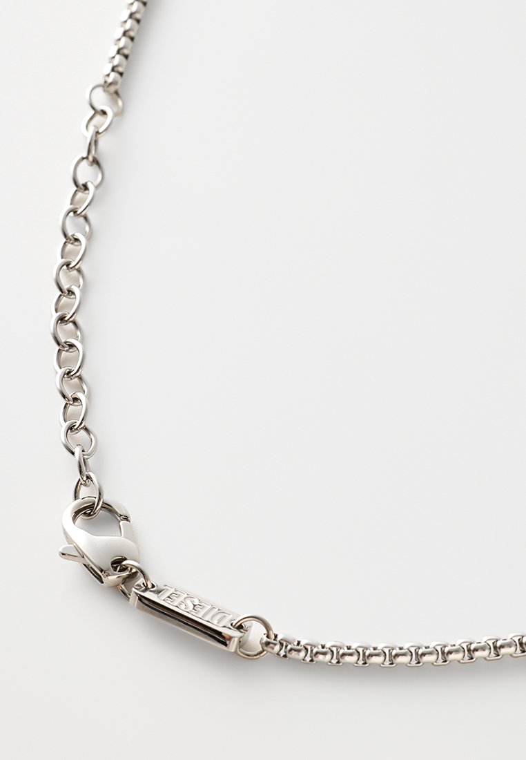 Collana in argento con chiusura a granchio e un piccolo cartellino inciso con la scritta "DIESEL" su uno sfondo bianco semplice.