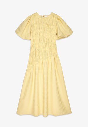 Kollase tekstuuriga riietus, millel on kokkukogutud detailid, lühikesed puhv-õlad ja mugav lõige. Keskmise säärte pikkus, ümmargune kaelus.