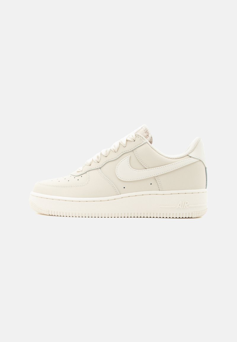 Μπεζ αθλητικό παπούτσι χαμηλού τύπου Nike Air Force 1 με κλείσιμο με κορδόνια και λαστιχένια σόλα, εμφανιζόμενο από την εξωτερική πλευρά σε λευκό φόντο.