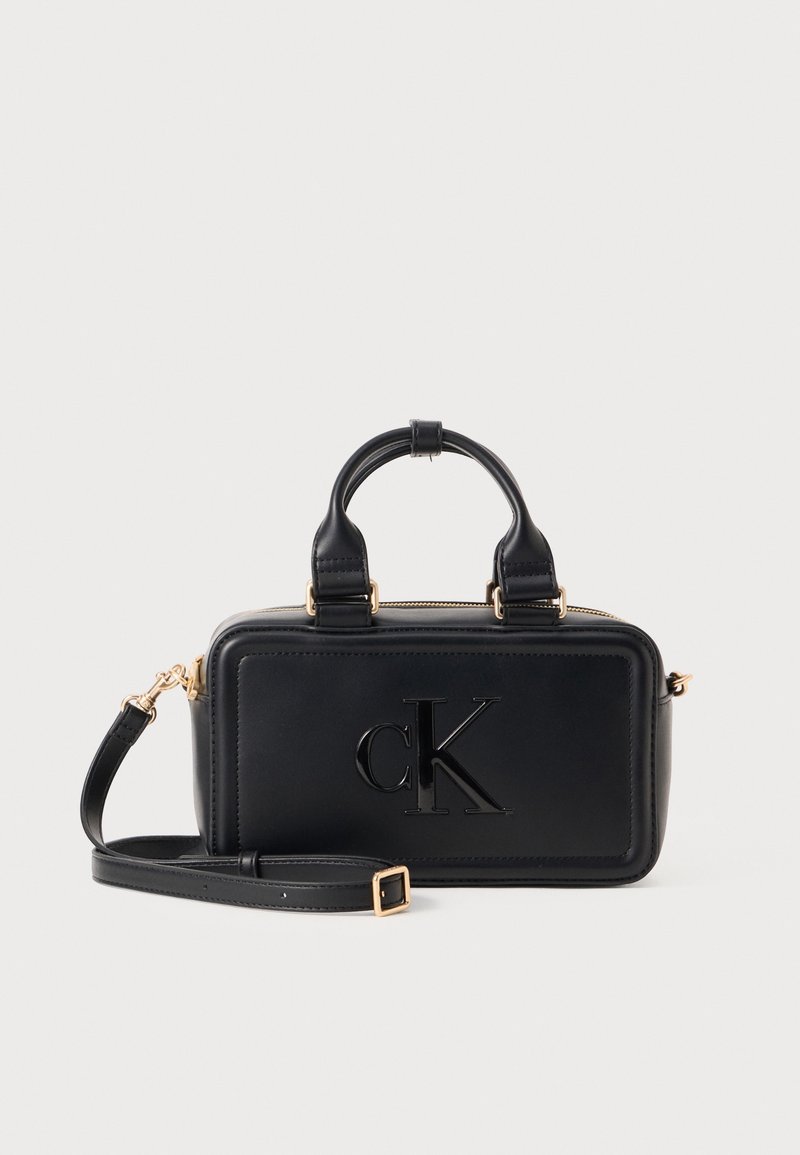 Sac à main rectangulaire noir avec poignées courtes et bandoulière réglable, avec logo cK en relief sur le panneau avant.