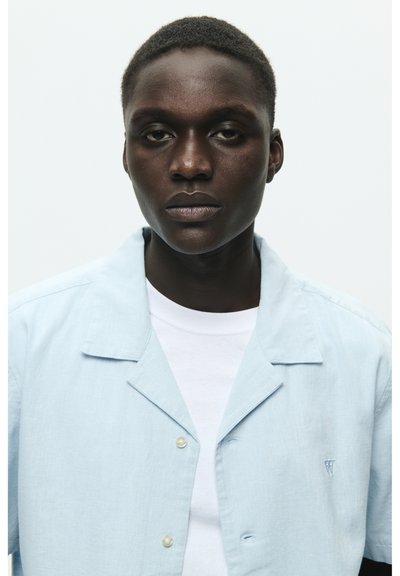 Chemise à manches courtes, bleu clair, en tissu texturé, avec un col cranté et un petit logo brodé.