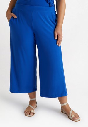 Culottes larges et bleus en tissu léger avec une texture lisse, dotées de poches latérales et d'une taille ajustée.