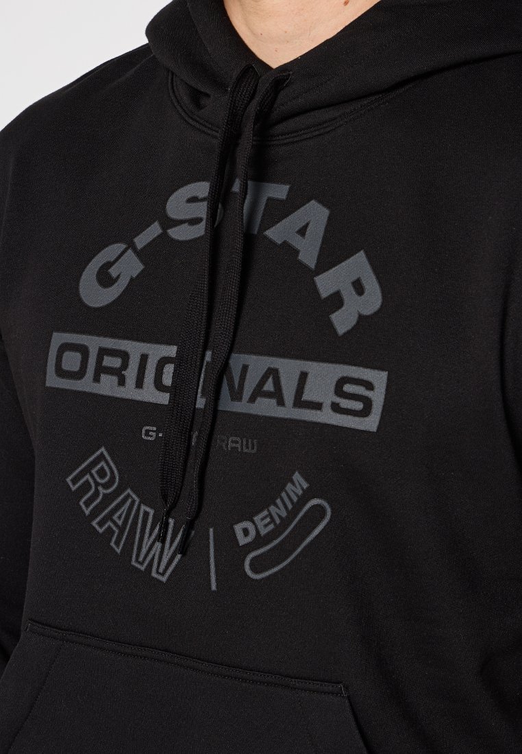 Sudadera con capucha negra hecha de tejido suave, que presenta un gran diseño de texto gráfico en gris que incluye detalles de marca y producto.