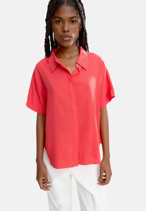 Koralikowa koszula z krótkim rękawem i kołnierzykiem zapinanym na guziki, wykonana z gładkiego materiału. Posiada luźny krój oraz detal w postaci podwinięcia przy rękawach.
